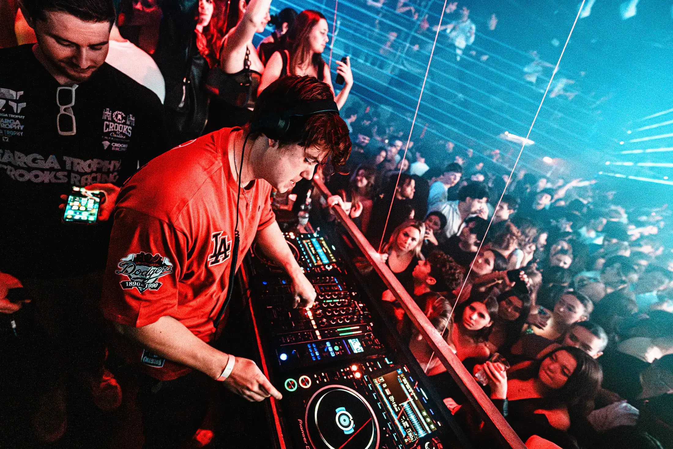 A DJ performing in a packed club under blue and orange stage lighting
