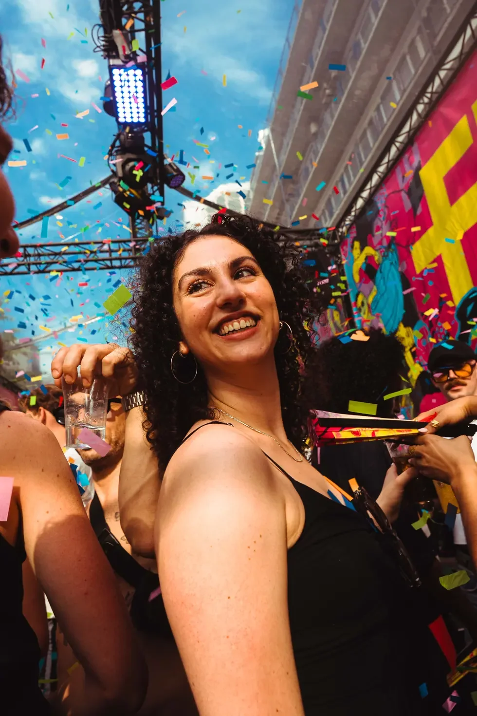 Person smiling under confetti at an outdoor event