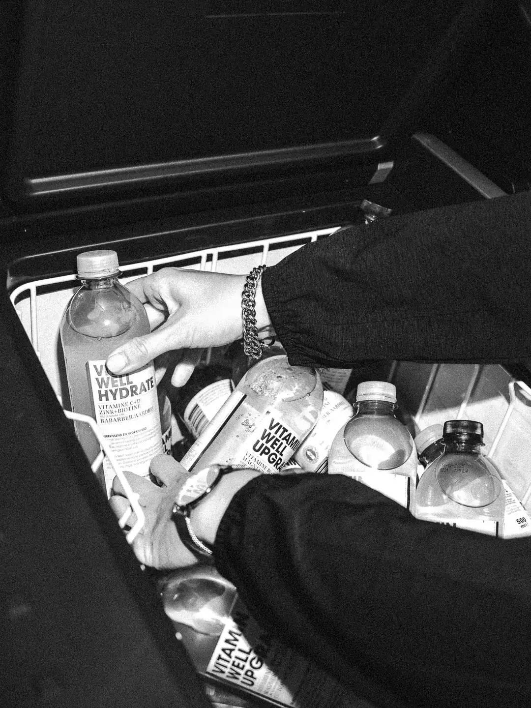 Hands picking up Vitamin Well bottles from a cooler during a brand activation