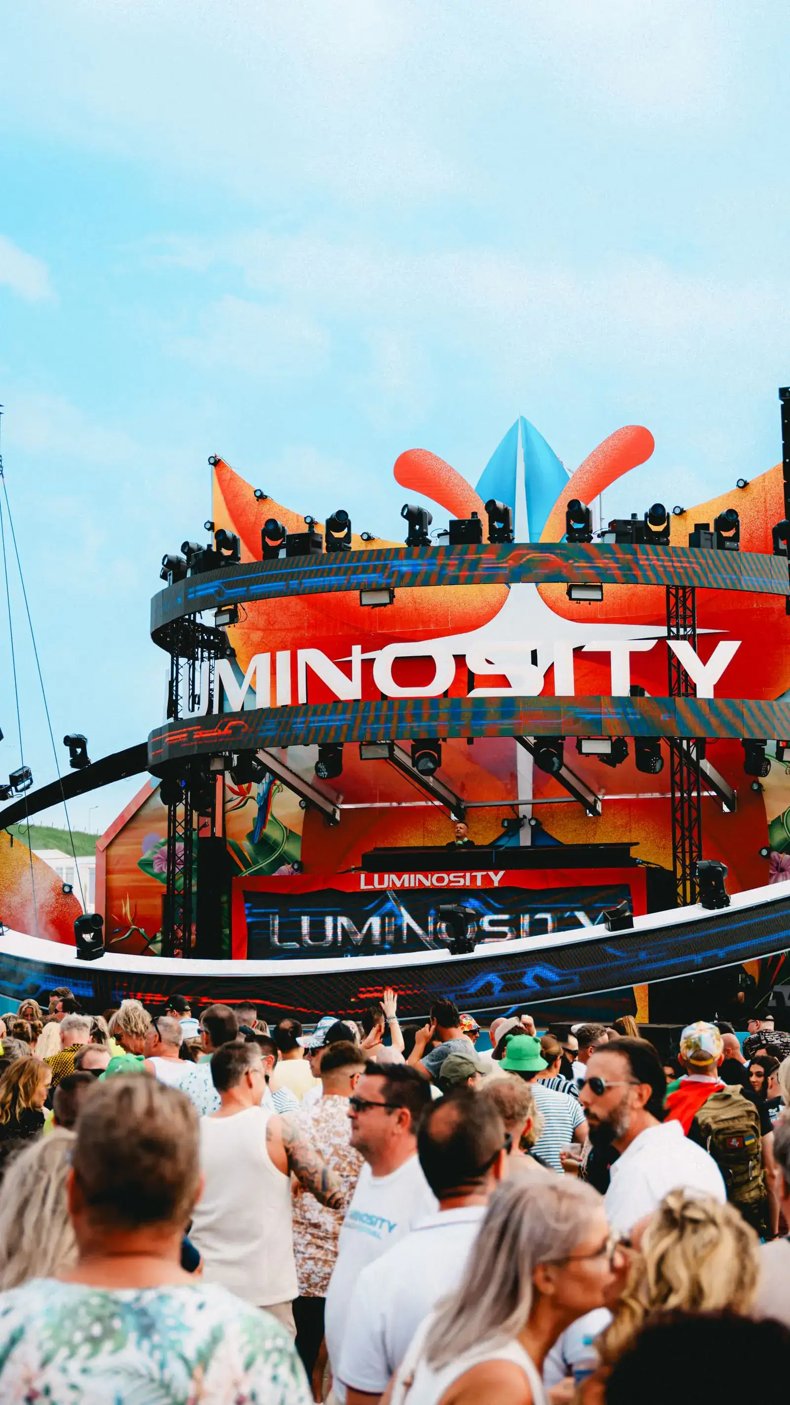 Festival crowd in front of a stage with warm lights and smoke